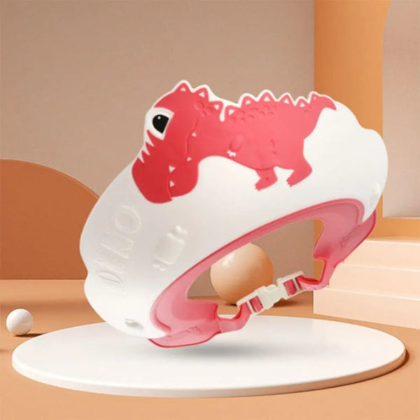 The Adjustable Dinosaur Baby Shower Cap for Kids by Alaya Junior is a pink and white headguard designed with child-friendly materials. It features charming cartoon dinosaur details and is showcased on a circular platform against a soft beige and orange backdrop, making it ideal for bath time protection.