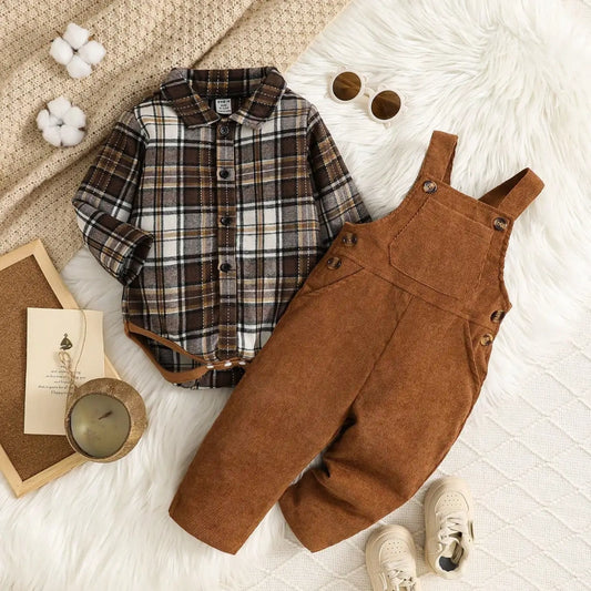 Children's plaid shirt and brown overalls on a textured surface with books and a candle.
