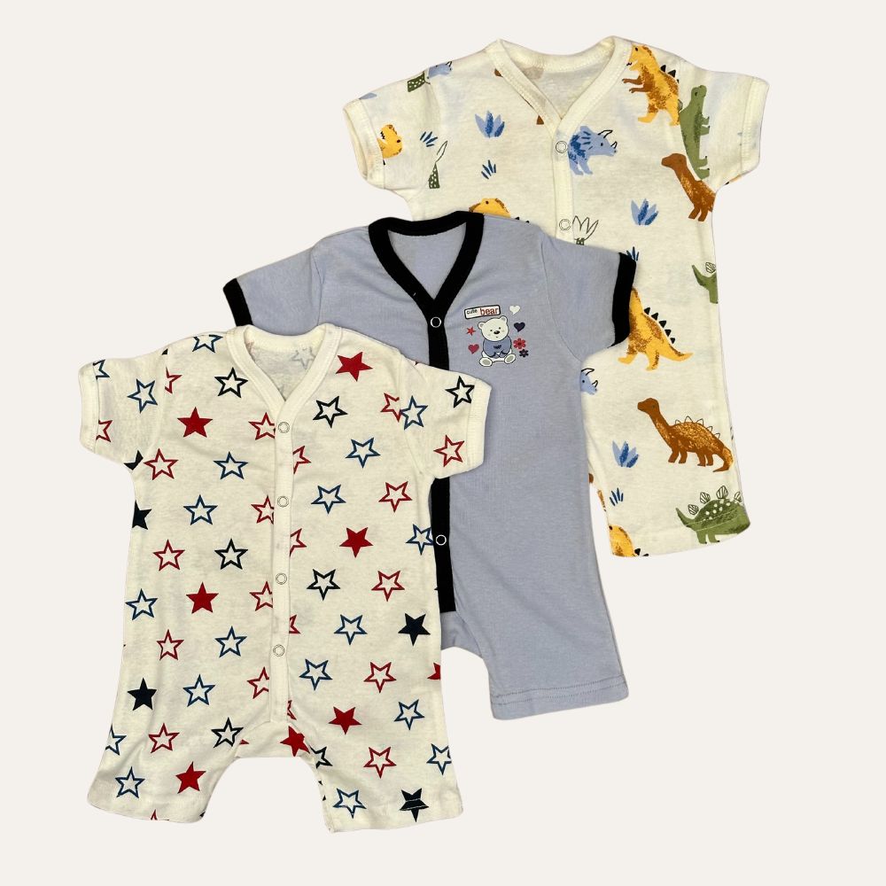Three baby onesies from the Baby Boy Pack of 3 Summer Half Sleeve Romper by Alaya Junior are displayed. The first is white with red, blue, and black stars. The second is gray with black trim and a cartoon bear patch. The third is white with various colorful dinosaur prints. All onesies have short sleeves and snap closures—perfect for newborn baby clothing in Pakistan.