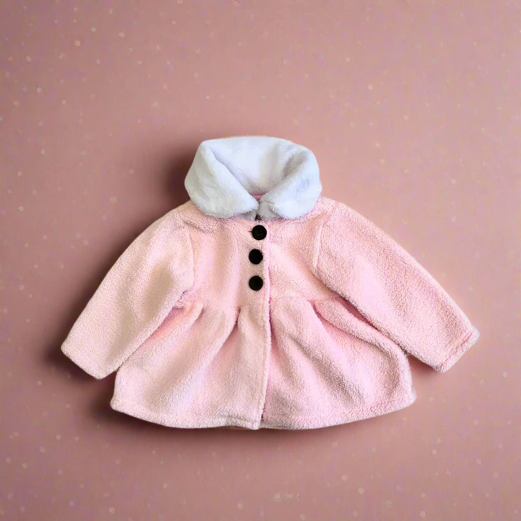 An Alaya Junior Baby Girl Sherpa Winter Cardigan with a faux fur collar, featuring pastel blue and pink hues and black buttons, is laid flat on a soft pink polka dot background.