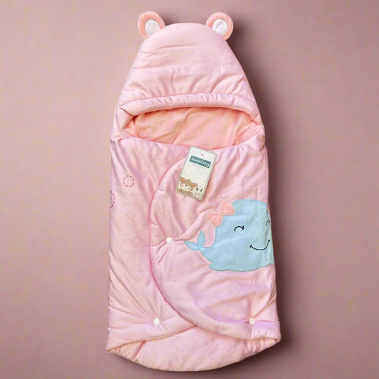 Pink baby swaddle with whale design and bear ears on a white background