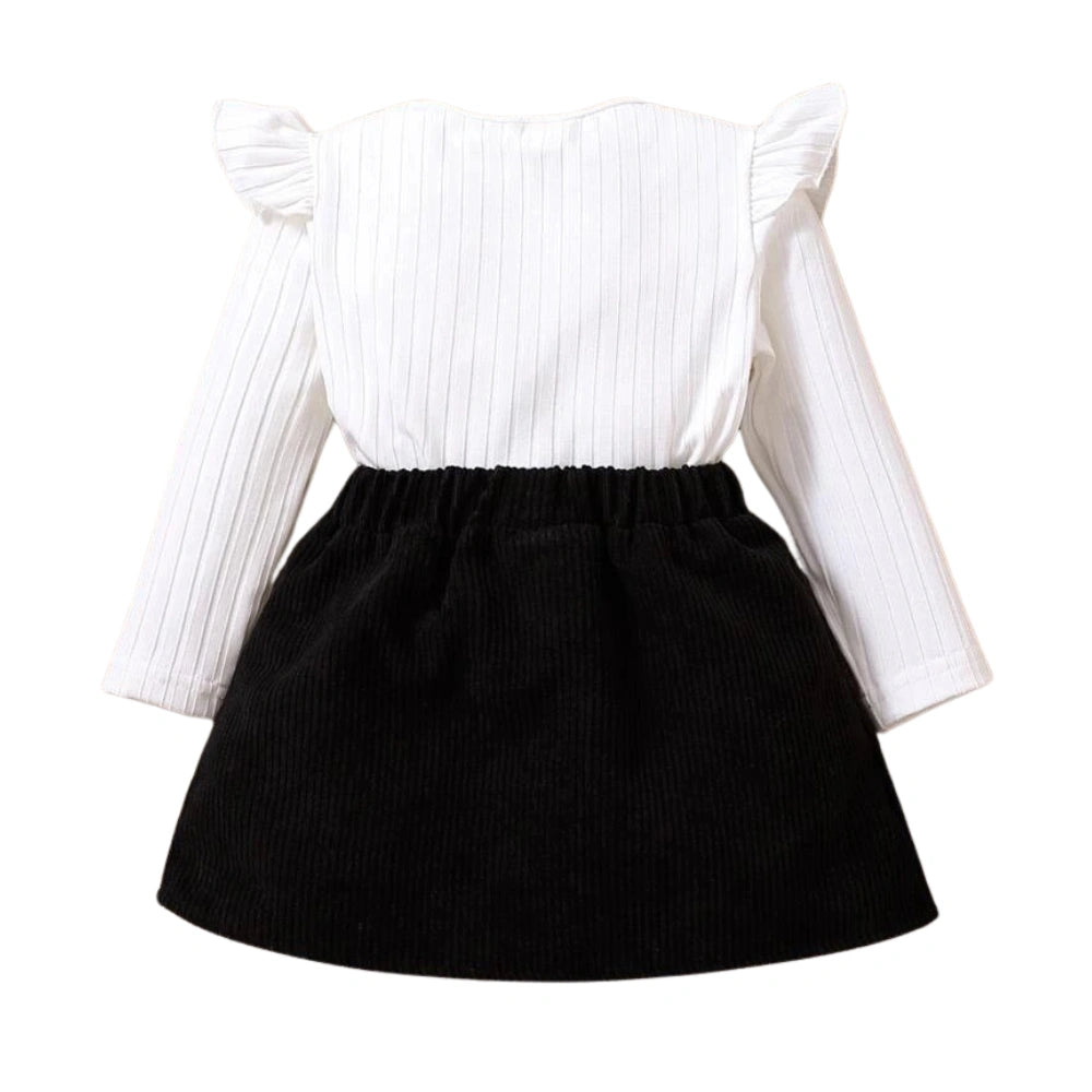 The SHEIN Baby Girl Ruffle Trim Tee & Bow Front Skirt boasts a ribbed white top with ruffled shoulders and long sleeves, paired with a bow front skirt. Its simple, classic design elegantly merges textured fabrics for a stylish look.