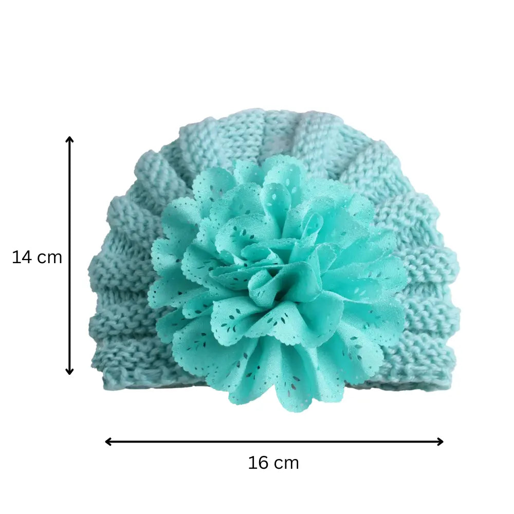 The Alaya Junior Baby Girl Lace Flower Design Knitted Turban Cap (0m - 3Yrs) in turquoise showcases a large decorative flower on the front. This stylish and versatile accessory measures 14 cm in height and 16 cm in width, making it perfect for keeping your little one both cozy and fashionable.