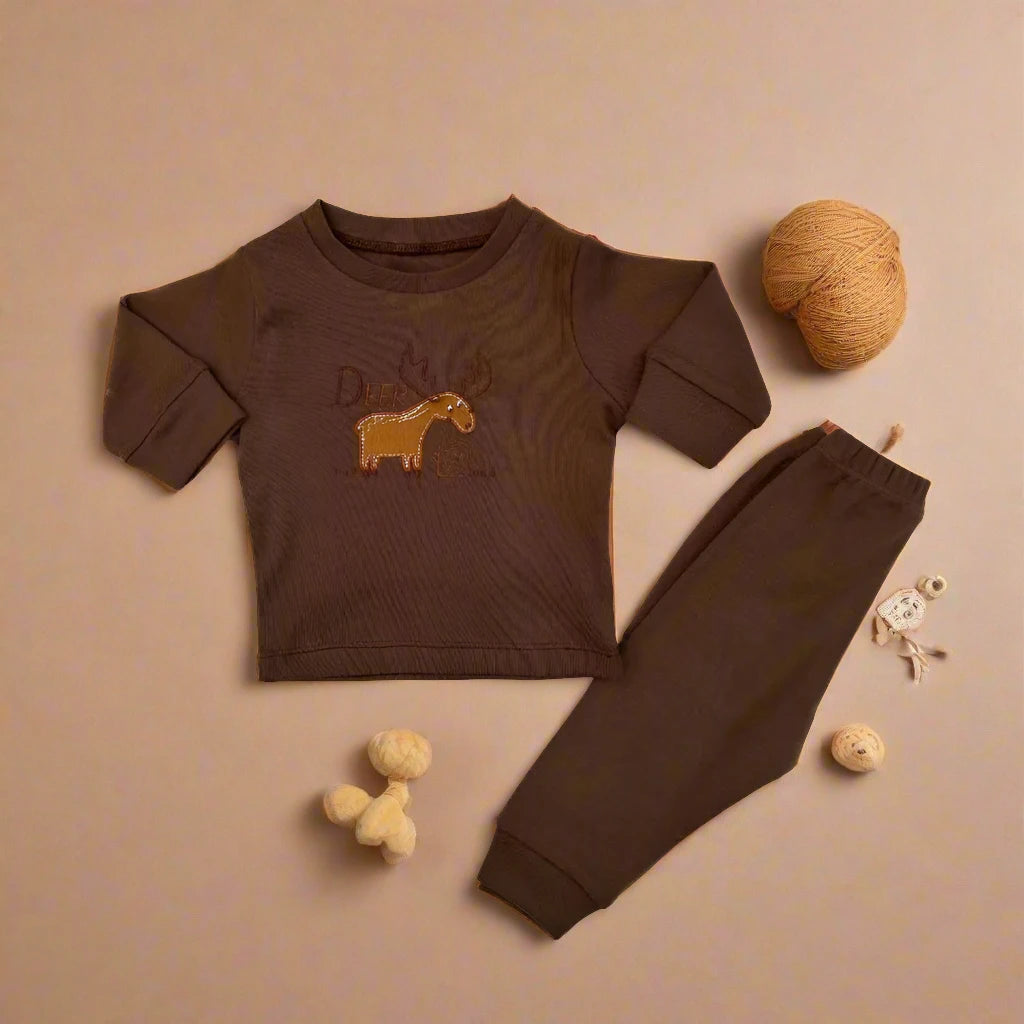 Alaya Junior's Unisex Baby 2 PCS Cotton Imported Shirt And Trouser Set is artfully displayed on a beige background, showcasing a brown long-sleeve shirt adorned with a yellow horse design, paired with coordinating cotton pants. Completing the charming arrangement are two balls of yarn and an adorable sheep-shaped toy, perfect for enhancing any little one's wardrobe.