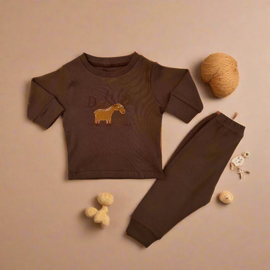 Alaya Junior's Unisex Baby 2 PCS Cotton Imported Shirt And Trouser Set is artfully displayed on a beige background, showcasing a brown long-sleeve shirt adorned with a yellow horse design, paired with coordinating cotton pants. Completing the charming arrangement are two balls of yarn and an adorable sheep-shaped toy, perfect for enhancing any little one's wardrobe.