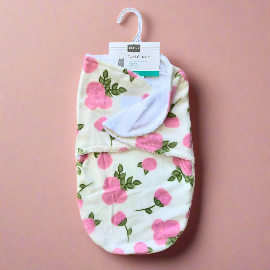 The Cozy Winter Swaddle with Pink Floral Design by Alaya Junior is displayed on a hanger against a pink background. The wrap, intended for infants, is neatly folded to highlight its soft texture and charming floral pattern, providing warmth for your baby.