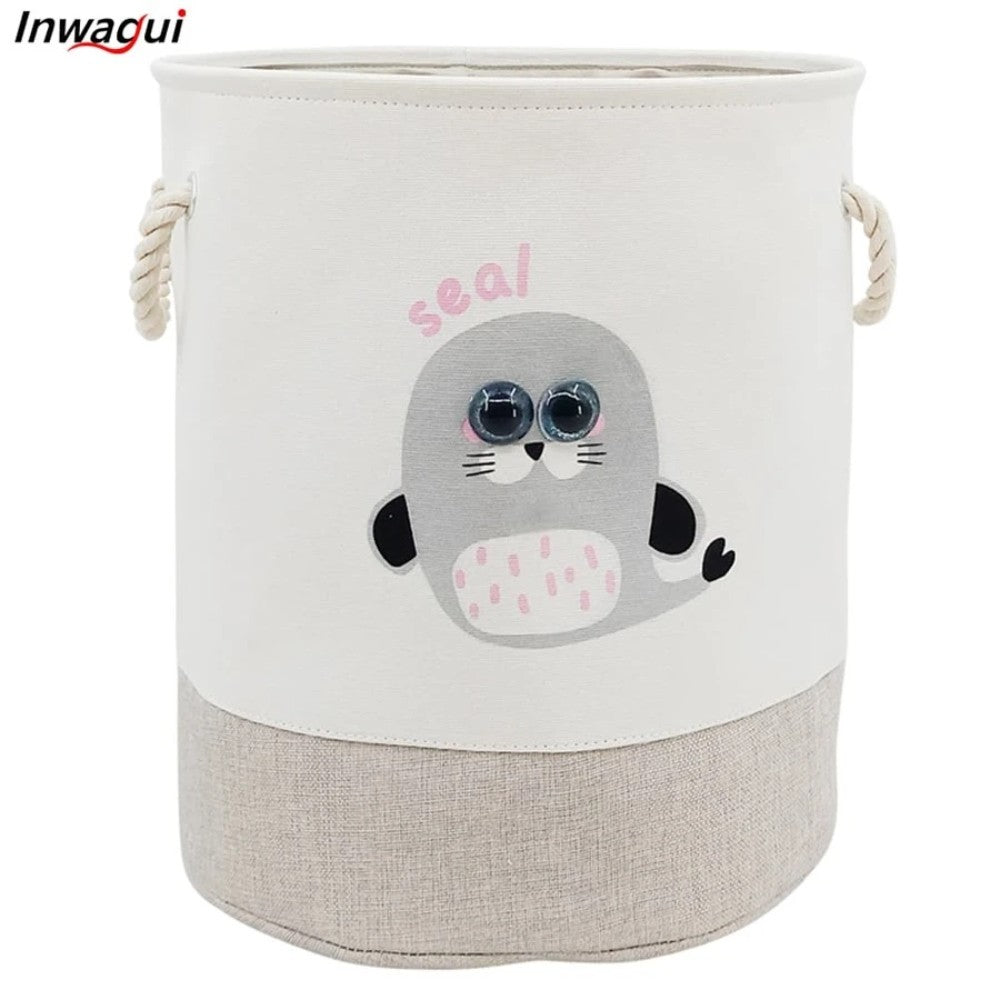 The SHEIN Kids Large Folding Laundry Basket features a cute cartoon seal on its cylindrical, beige and white design. With rope handles and "seal" printed above the image, it's perfect for children's laundry needs.