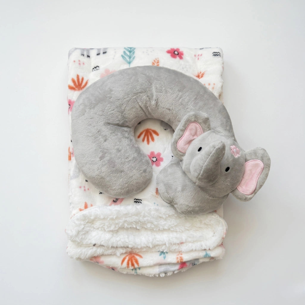 Gray elephant-shaped neck pillow on a floral-patterned blanket
