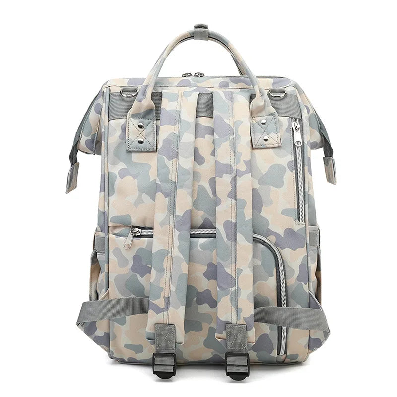 The Alaya Junior Versatile Mom Backpack, a Waterproof Camo Diaper Bag in gray and white tones, is designed with adjustable shoulder straps, top handles, and several pockets.