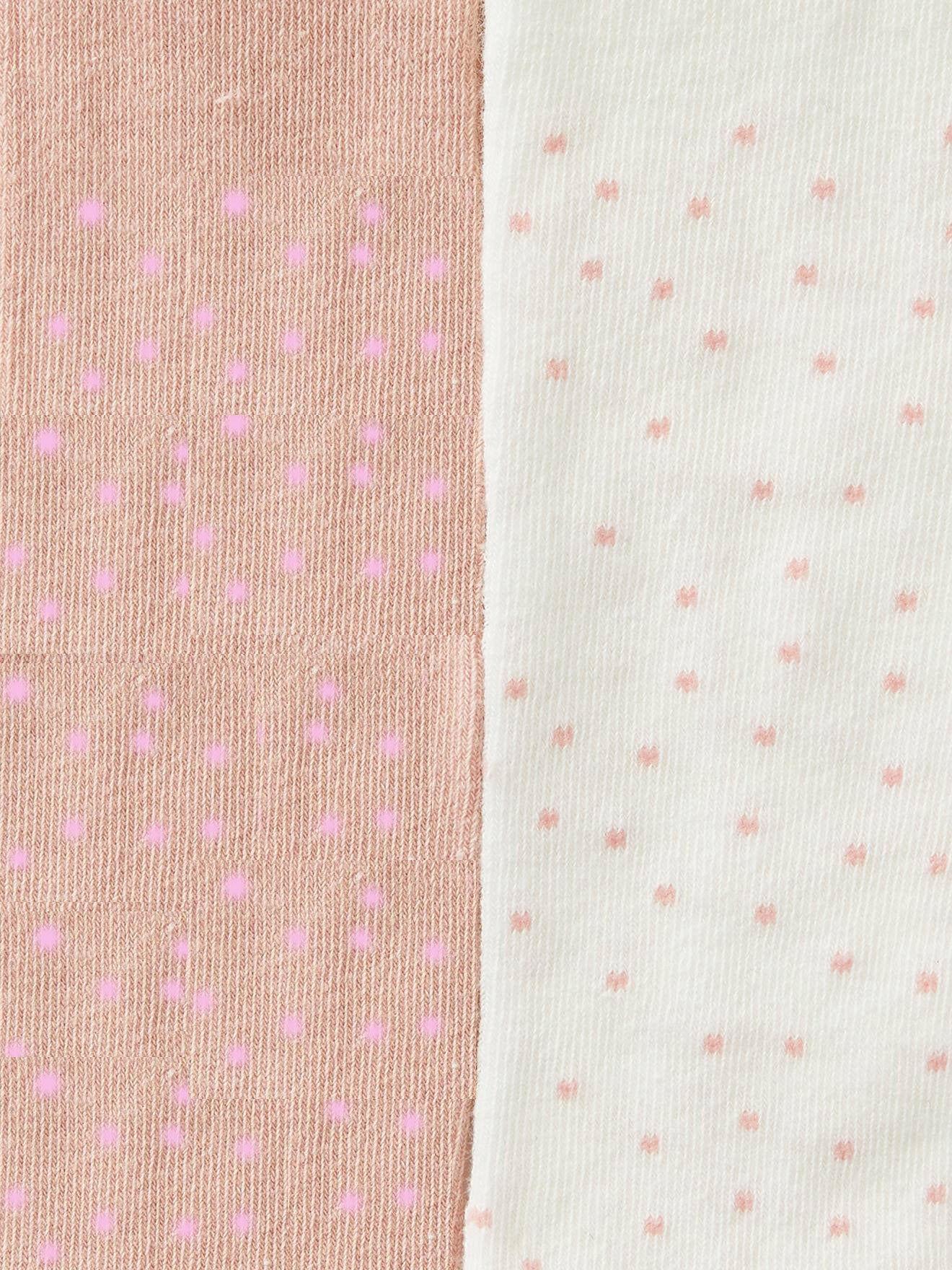 Close-up of two pieces of fabric side by side. The left fabric is peach-colored with small pink dots, while the right fabric is off-white with small light pink dots. Both fabrics feature a textured, ribbed pattern, ideal for Alaya Junior's 4-Pack Toddler Girl Winter Leggings in Spandex. Perfect for newborn baby clothing in Pakistan.