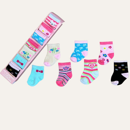 The "Week of Joy: Imported Pack Mix Baby Socks Gift Set (7 Pairs)" by Alaya Junior features an adorable collection of baby socks in vibrant colors and delightful patterns such as stripes, flowers, hearts, and stars. Each pair is crafted from high-quality materials and comes neatly packaged, with purple baby socks adding a playful element to the assortment.