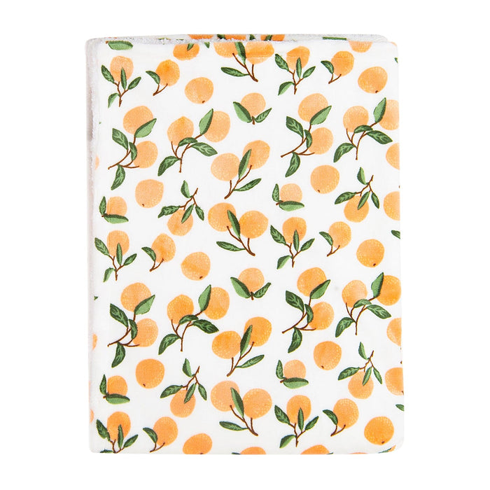 A blanket with a colorful citrus motif cover. The white background features an array of illustrated oranges with green leaves, creating a fresh and vibrant design. The edges of the Luvable Friends' Citrus Bliss: Unisex Sherpa-Backed Plush Blanket by Alaya Junior are visible, indicating it is neatly folded and ready for use.