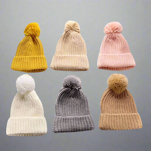 Six Alaya Junior 6M-5YRS Kids Winter Hats, expertly designed with faux fur pom-poms, are perfect for winter adventures and displayed in two rows against a gray background. The top row showcases the colors mustard, beige, and pink, while the bottom row features white, gray, and brown. Each beanie is crafted from soft knitted cotton acrylic fabric that stretches for maximum comfort.