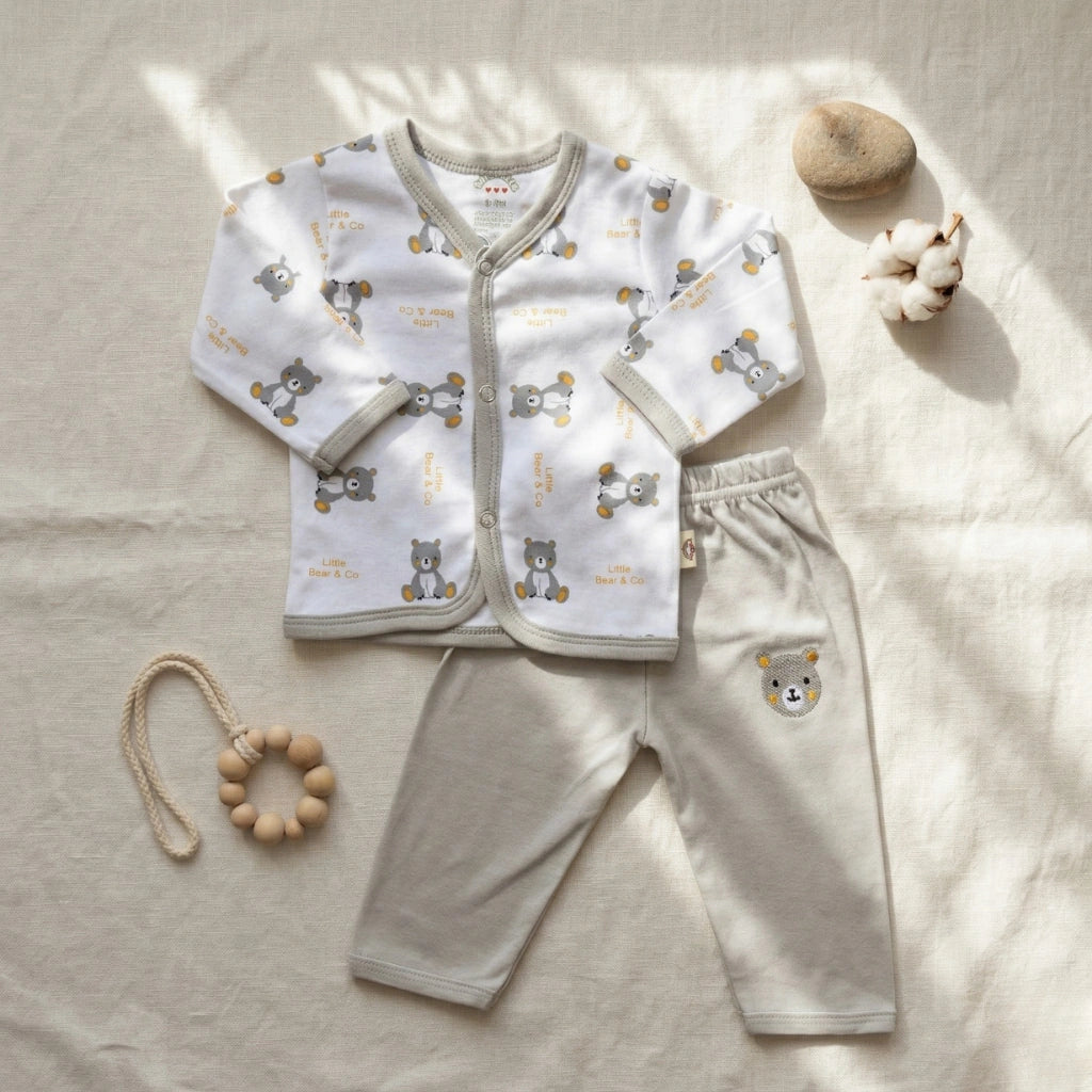 Baby outfit set with shirt and pants on a light surface, accompanied by a wooden toy.