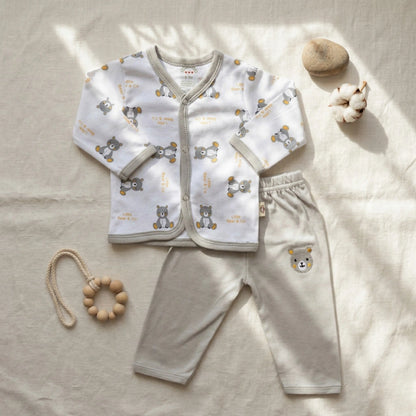Baby outfit set with shirt and pants on a light surface, accompanied by a wooden toy.