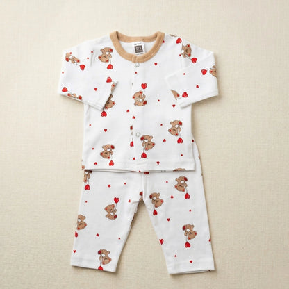 Children's pajama set with teddy bear and heart pattern on a beige background