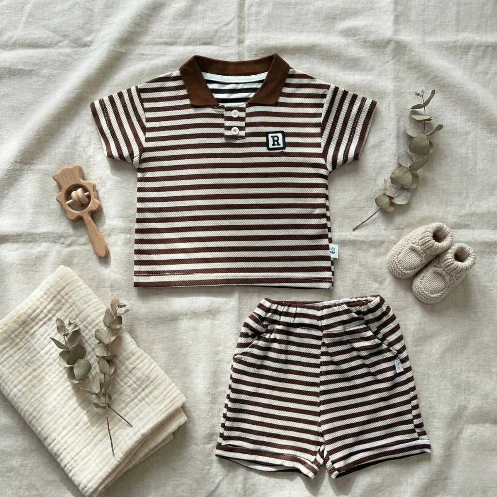 Children's striped shirt and shorts set with baby shoes and a blanket on a light background
