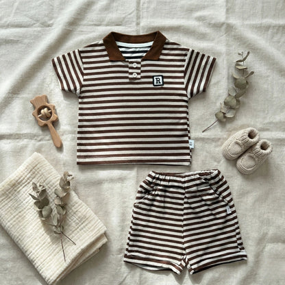 Children's striped shirt and shorts set with baby shoes and a blanket on a light background