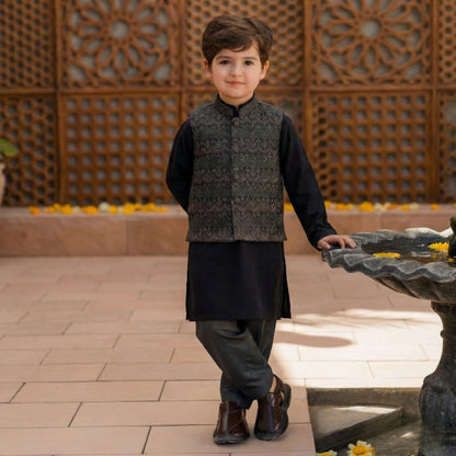 Young boy in traditional attire standing near a decorative fountain.