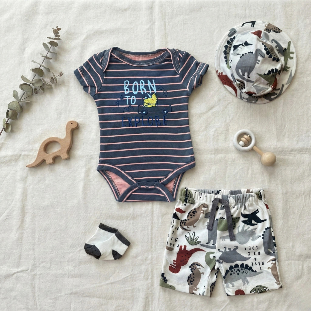 Baby clothing set with striped onesie, shorts, and accessories on a textured surface.