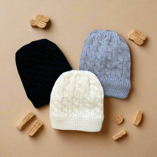 Three knit beanie hats in black, white, and gray on a white background
