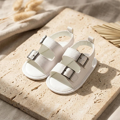 White sandals with buckles on a stone surface