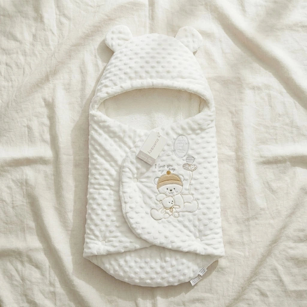 White baby swaddle with bear design on a soft beige blanket
