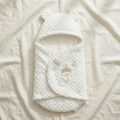 White baby swaddle with bear design on a soft beige blanket