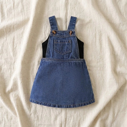 Blue denim pinafore dress on a beige fabric background