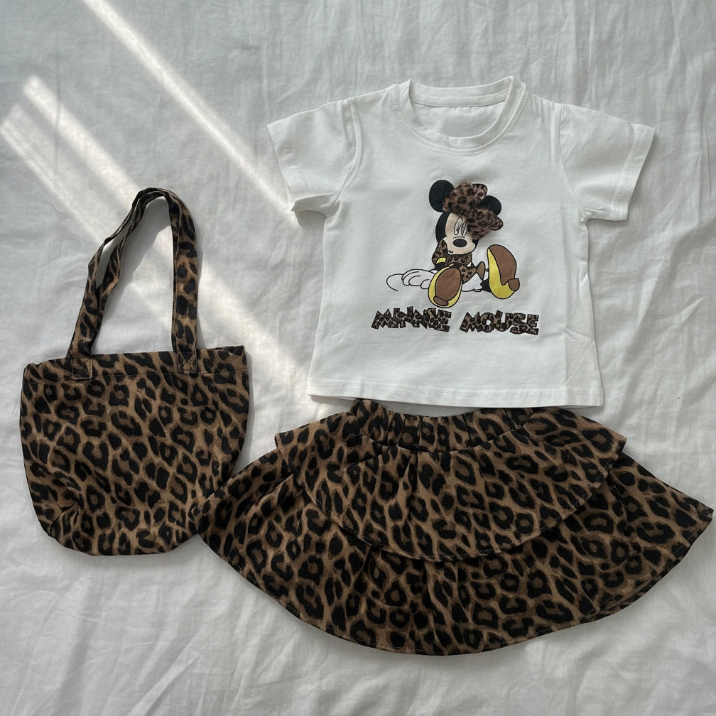 White t-shirt with cartoon character, leopard print skirt, and tote bag on a white background