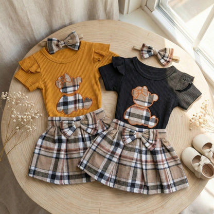 Two children's outfits with teddy bear designs on a wooden surface.