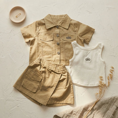 Children's beige shirt and shorts set with white tank top on a light background