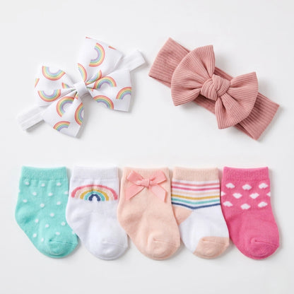 Set of baby accessories including socks and headbands with rainbow and bow designs on a white background.
