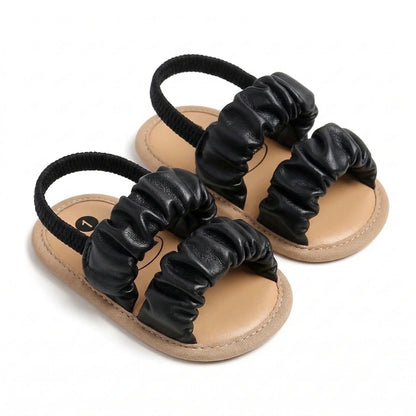 Pair of black scrunchie sandals on a white background