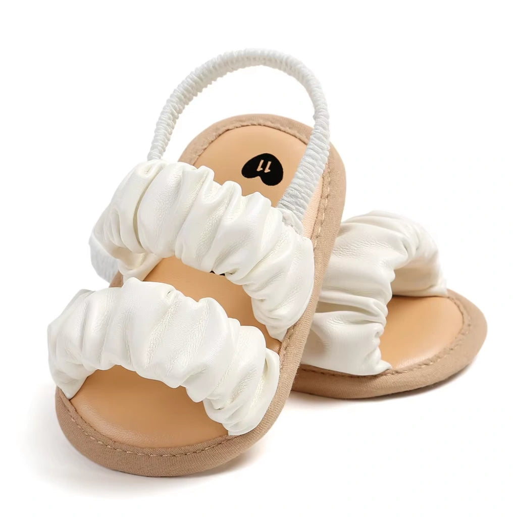 Pair of baby sandals with white ruffled straps on a white background