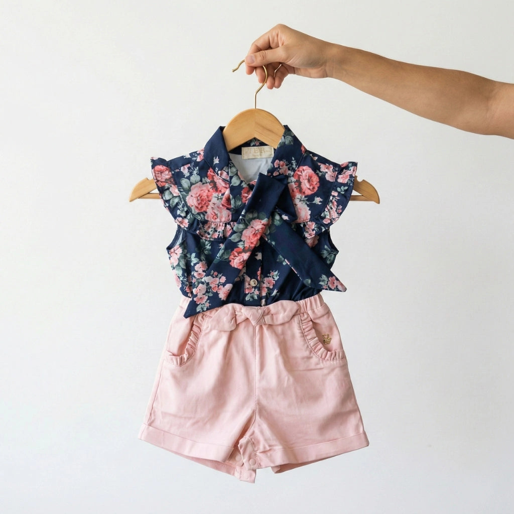 Floral top and pink shorts on a hanger against a white background