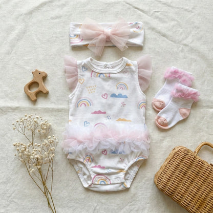 Baby outfit set with romper, headband, socks, and teether on a light background