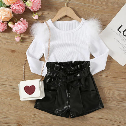 White --White long-sleeve top with fluffy shoulders, black paperbag waist shorts, and a small white bag with a red heart on a wooden surface.