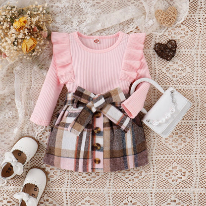 Children's outfit with pink top and plaid skirt on a lace background