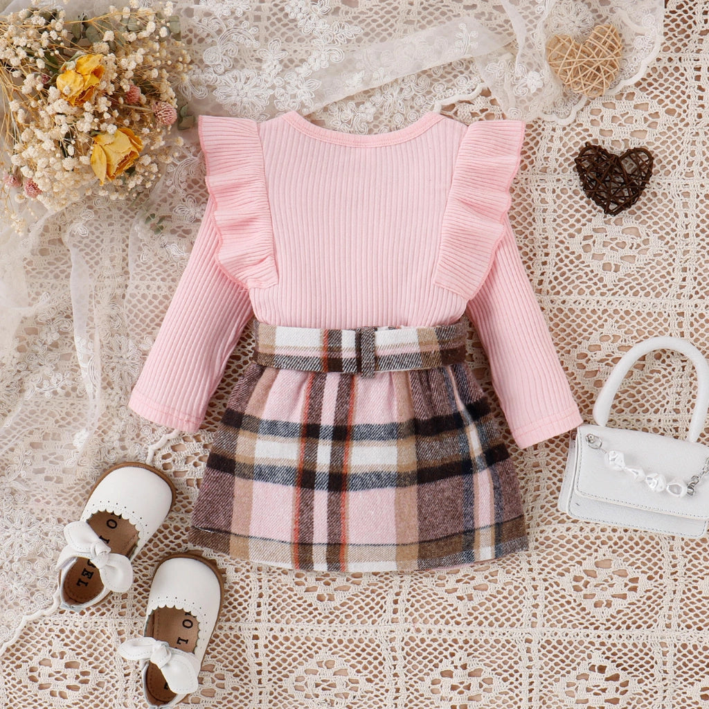 Pink sweater with plaid skirt and white shoes on a lace background