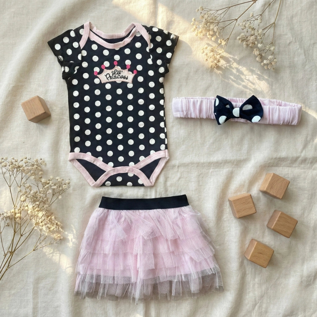 Baby outfit set with polka dot onesie, tutu skirt, and headband on a neutral background.