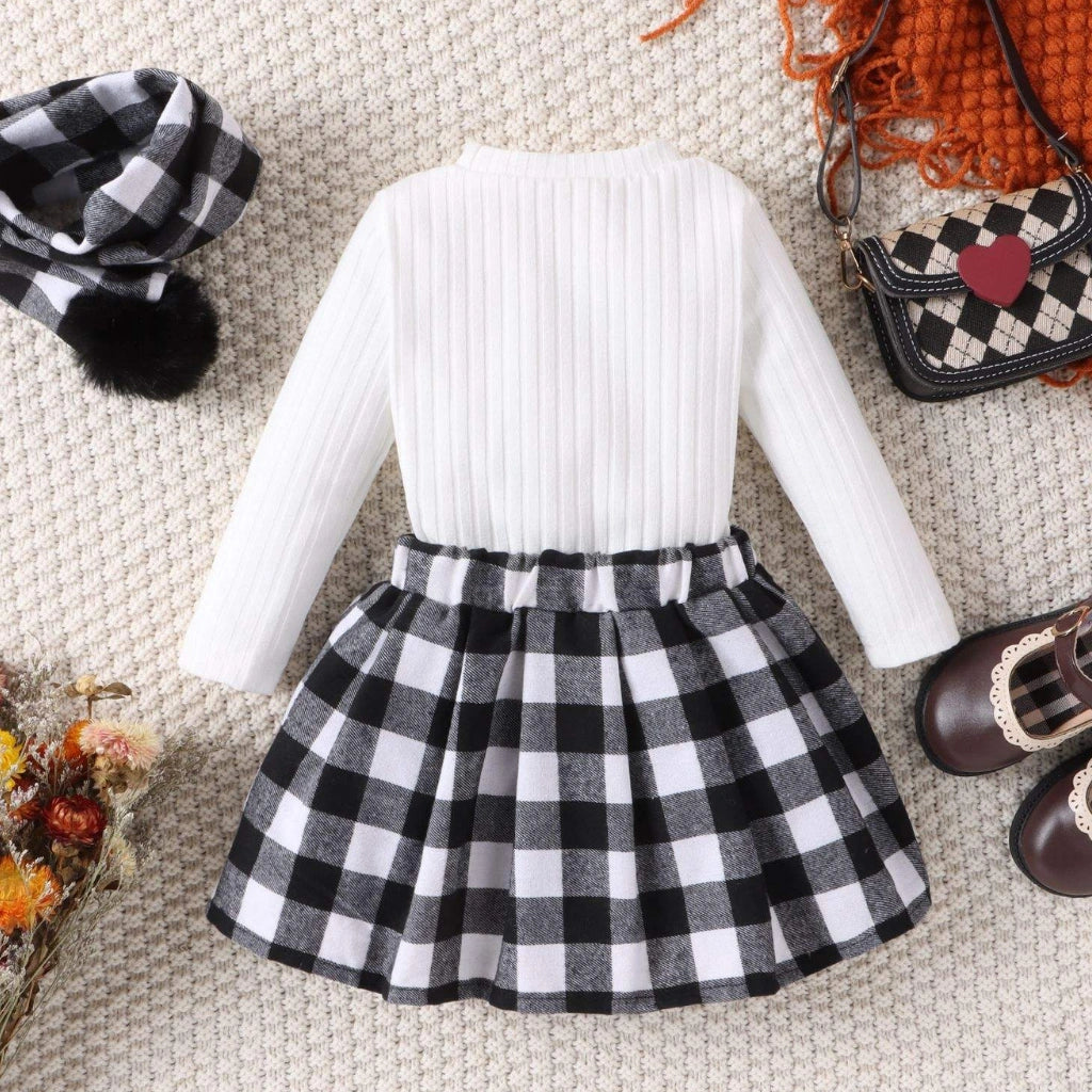 Black --- White long-sleeve top and black and white checkered skirt on a textured surface with accessories.