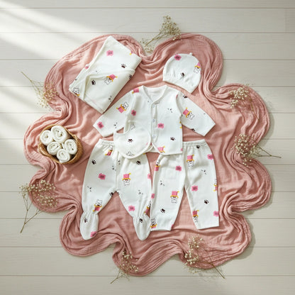 Baby clothing set with pink blanket and flowers on a wooden floor