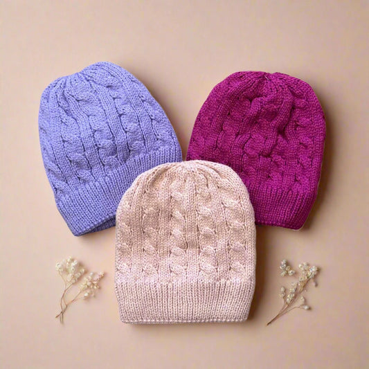 Three knitted hats in purple, pink, and beige on a white background