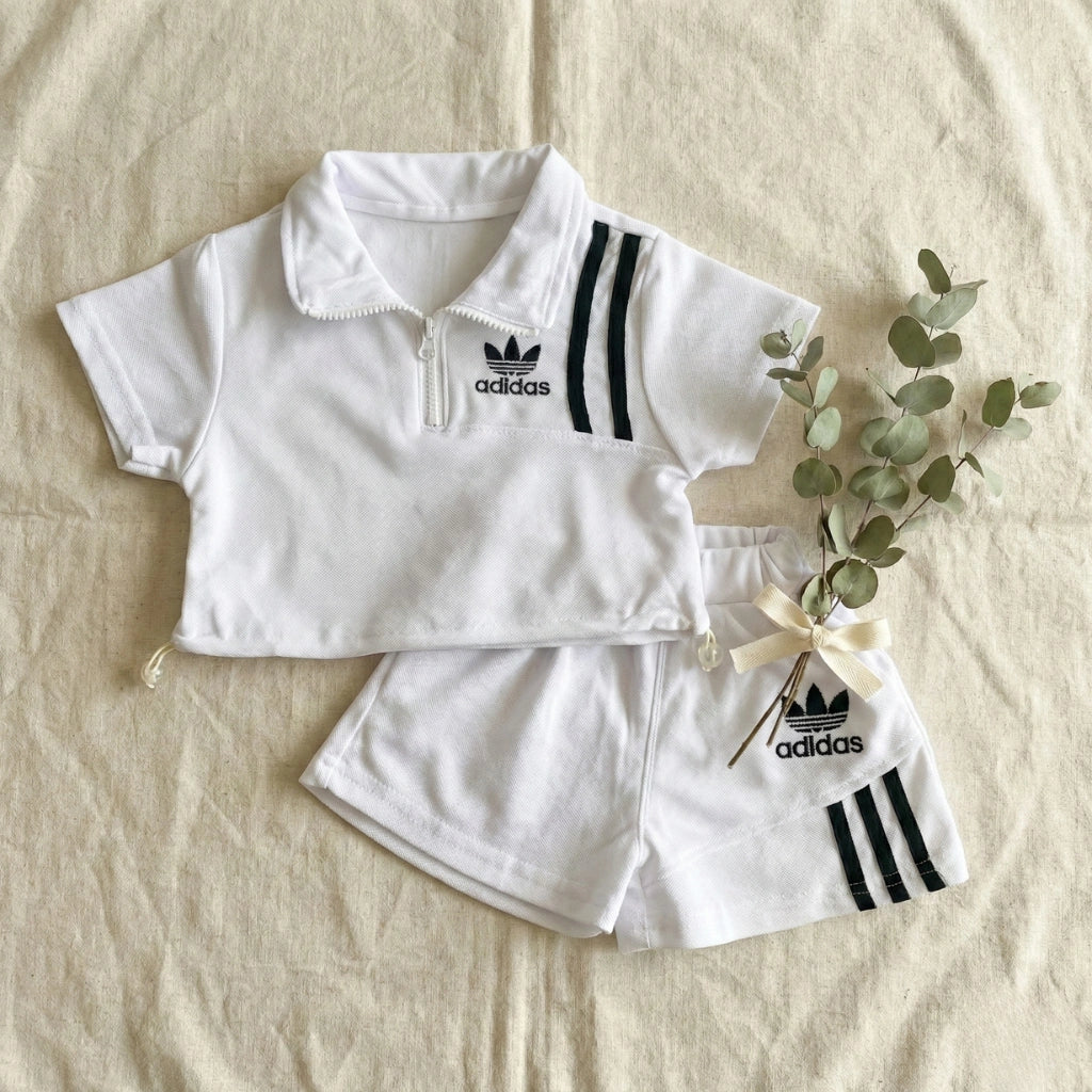 White Adidas children's outfit with matching hat on a beige background