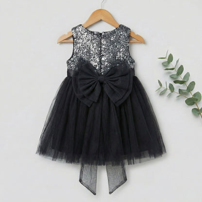 Black dress with sequin top and bow on a hanger against a white background