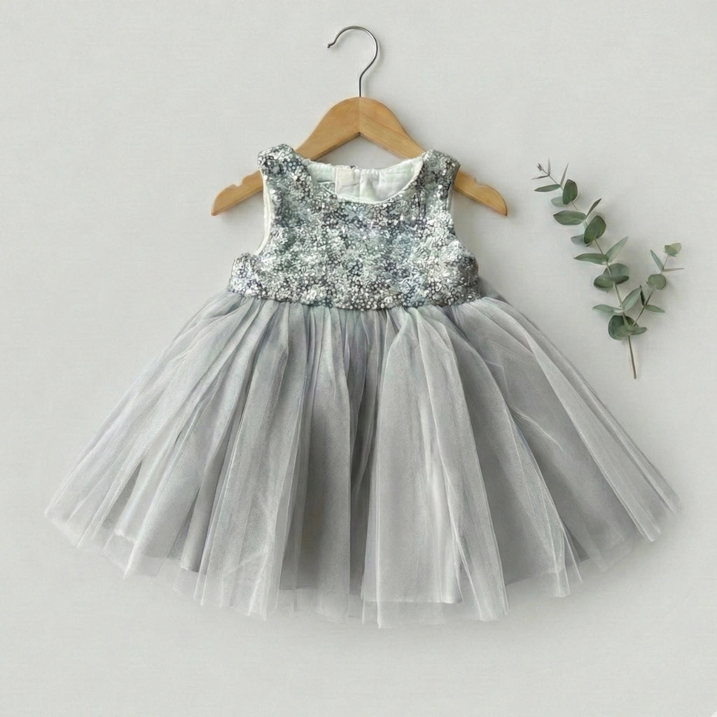 Children's dress with sequined top and tulle skirt on a hanger against a light background