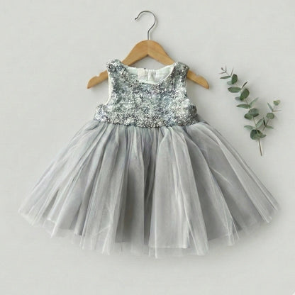 Children's dress with sequined top and tulle skirt on a hanger against a light background