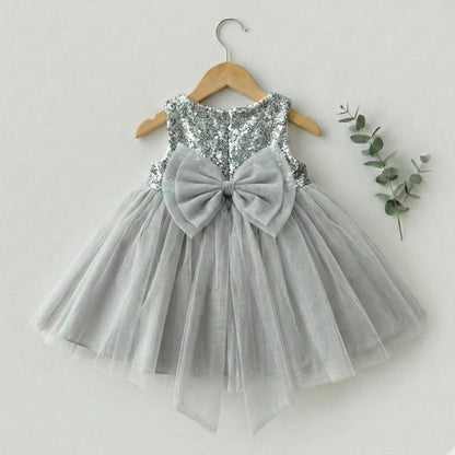 Gray sequin dress with a large bow on a hanger against a white background