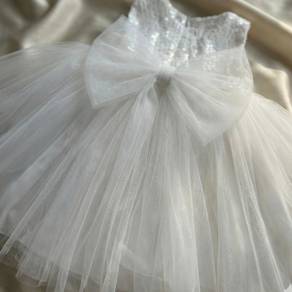 White tulle dress with a large bow on a neutral background